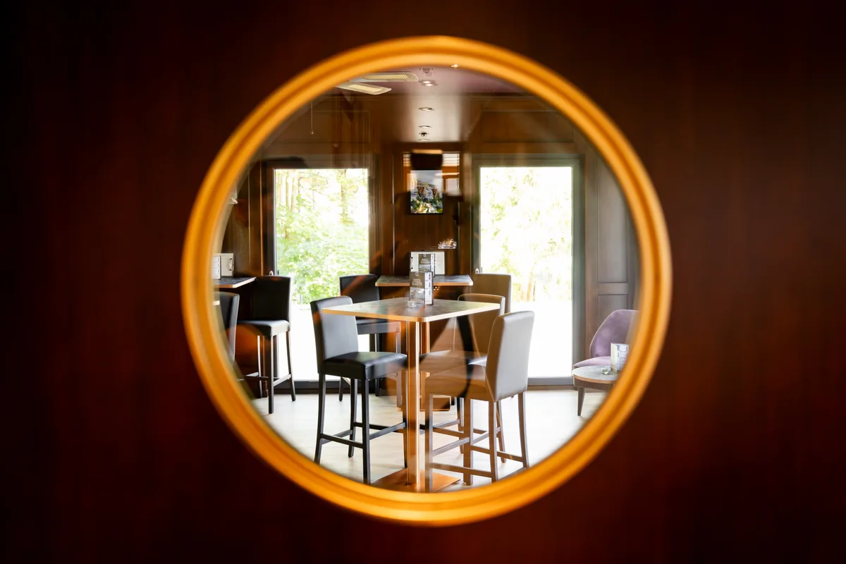 Ein Blick durch ein rundes Fenster auf ein paar Tische.